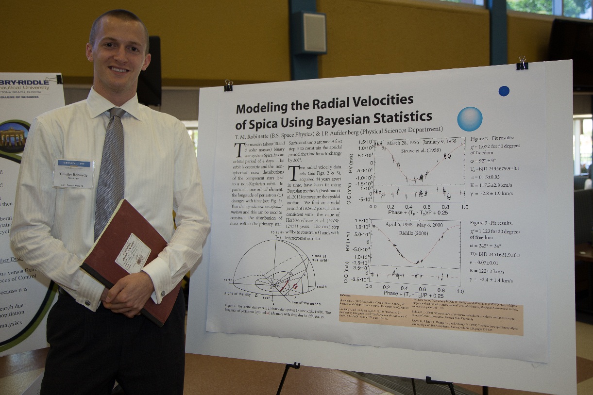 A student standing next to his poster